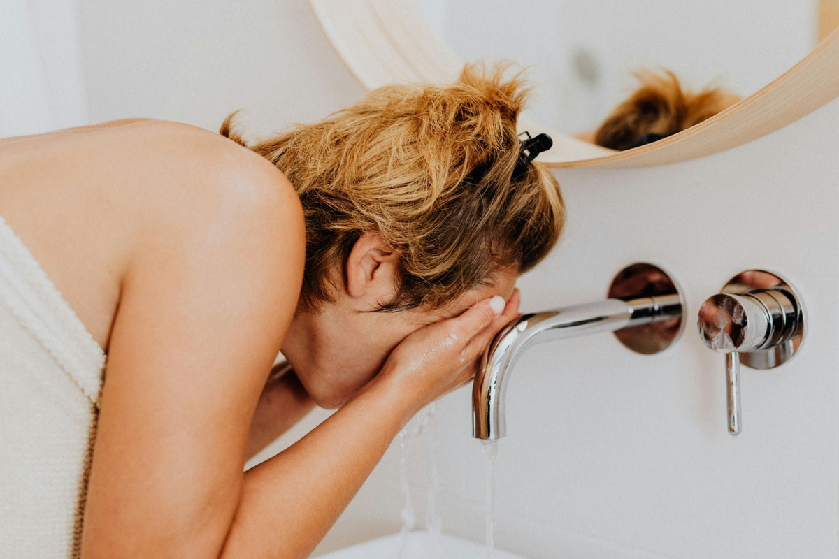 woman washing her face in the bathroom basin