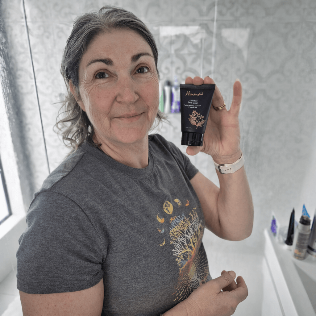 Woman holding a tube of Merindah Botanicals luxurious face cream in a bathroom setting