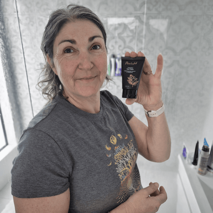 Woman holding a tube of Merindah Botanicals luxurious face cream in a bathroom setting