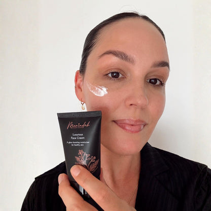 Woman applying face cream with a tube labeled &